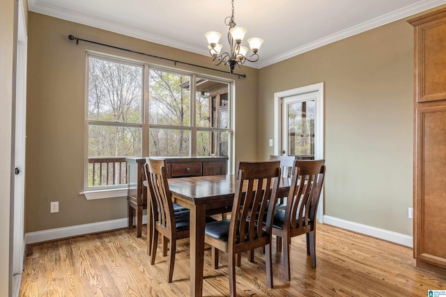 dining area with an inviting chandelier, ornamental molding, a healthy amount of sunlight, and light hardwood / wood-style flooring