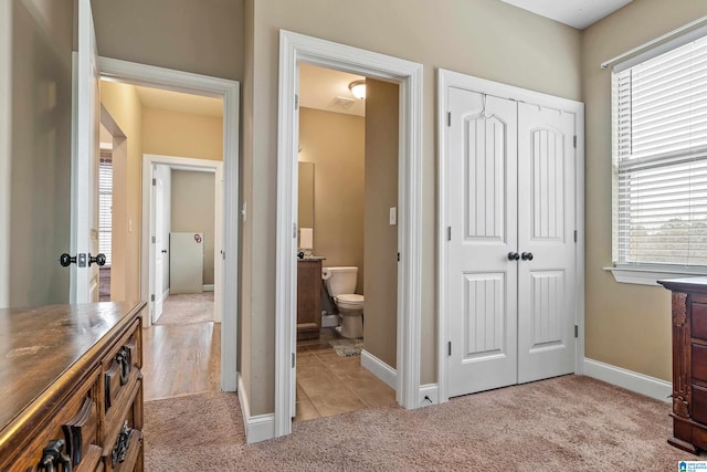 tiled bedroom with connected bathroom and a closet