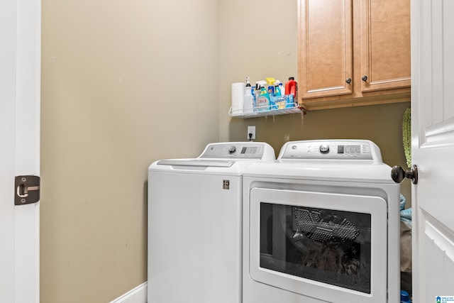 laundry room featuring washer and clothes dryer and cabinets