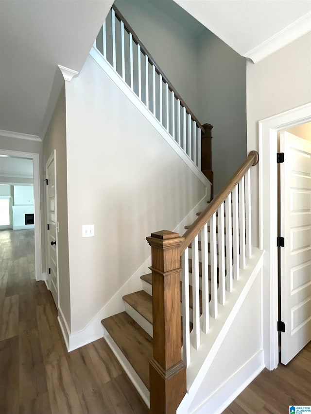 stairs featuring crown molding, baseboards, and wood finished floors