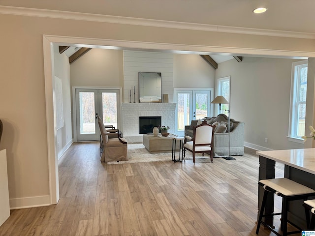 living area featuring vaulted ceiling with beams, light wood finished floors, and french doors