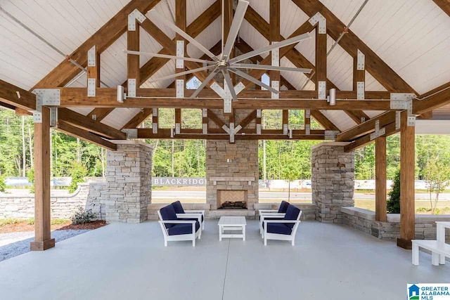 view of patio with ceiling fan, an outdoor stone fireplace, and a gazebo