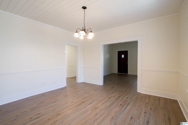 empty room with an inviting chandelier, light hardwood / wood-style flooring, and ornamental molding