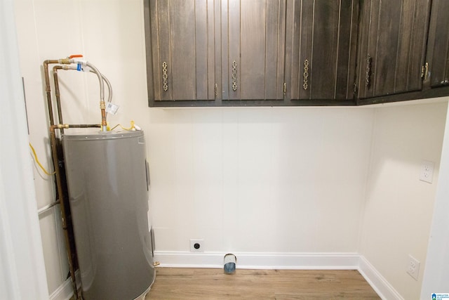 laundry area with light hardwood / wood-style floors, hookup for an electric dryer, and water heater