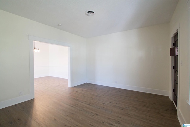 unfurnished room featuring an inviting chandelier and dark hardwood / wood-style flooring