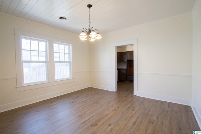 empty room featuring a chandelier, ornamental molding, and dark wood-type flooring