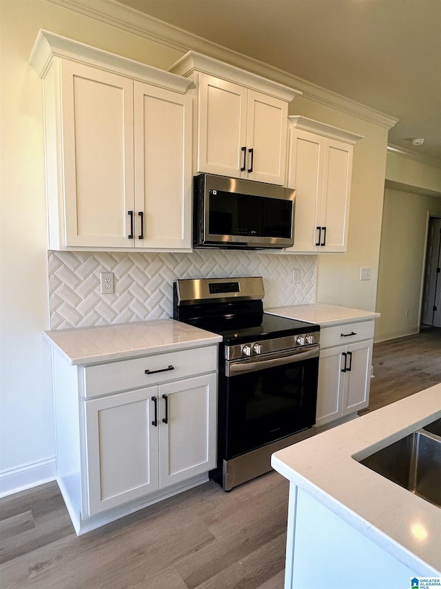 kitchen with decorative backsplash, white cabinets, and appliances with stainless steel finishes