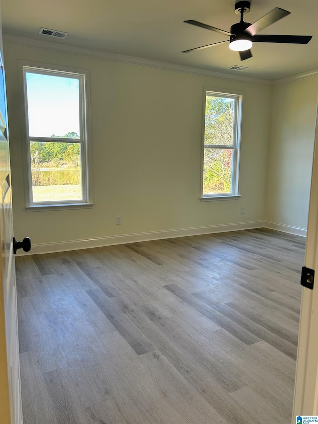 empty room featuring plenty of natural light, crown molding, and wood finished floors