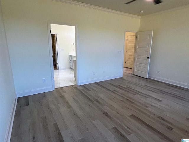 unfurnished bedroom featuring connected bathroom, wood finished floors, baseboards, and ornamental molding