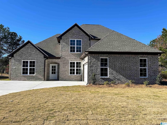 traditional home featuring driveway, a front lawn, roof with shingles, an attached garage, and brick siding