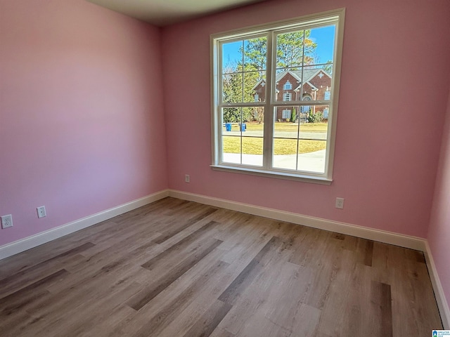 spare room featuring baseboards and wood finished floors