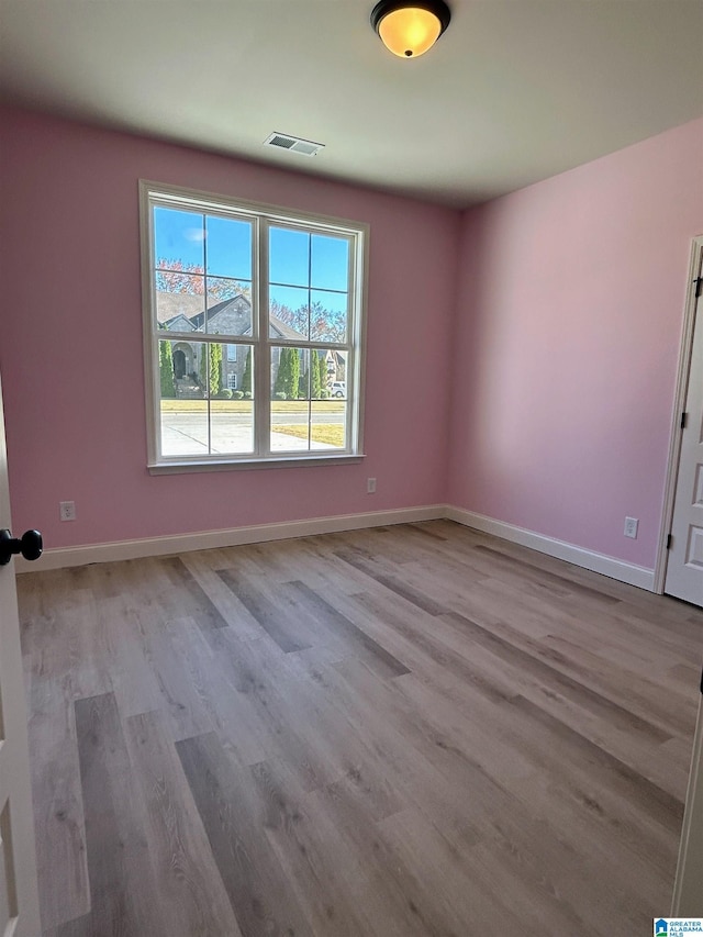 unfurnished room featuring wood finished floors, baseboards, and visible vents