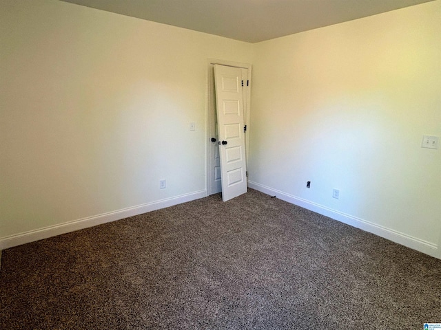 spare room featuring baseboards and dark colored carpet