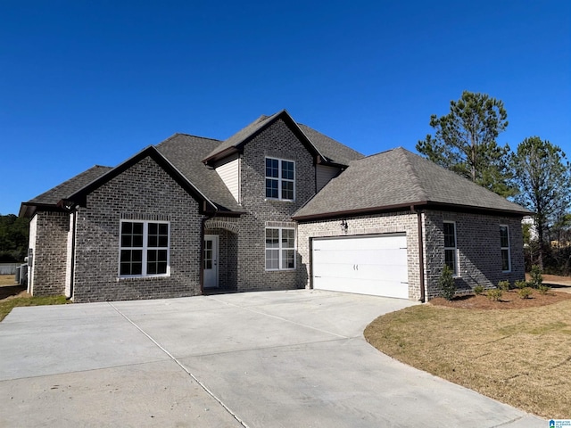 traditional-style home with driveway, a front yard, a shingled roof, a garage, and brick siding