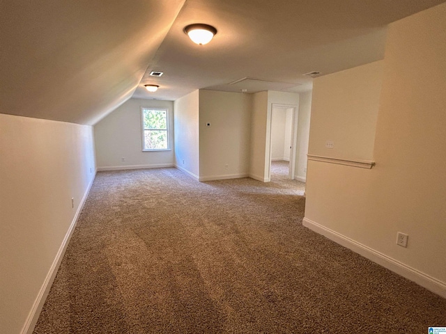 additional living space featuring baseboards, visible vents, light carpet, and lofted ceiling