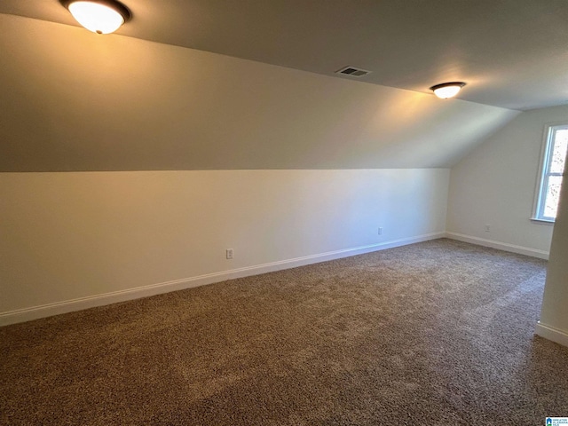 additional living space featuring vaulted ceiling, carpet, visible vents, and baseboards