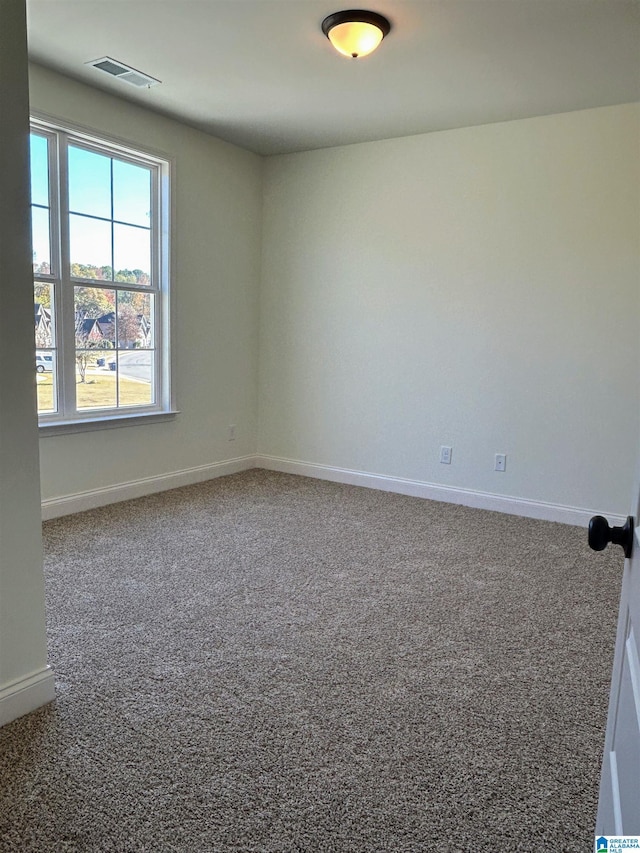 carpeted spare room featuring visible vents and baseboards