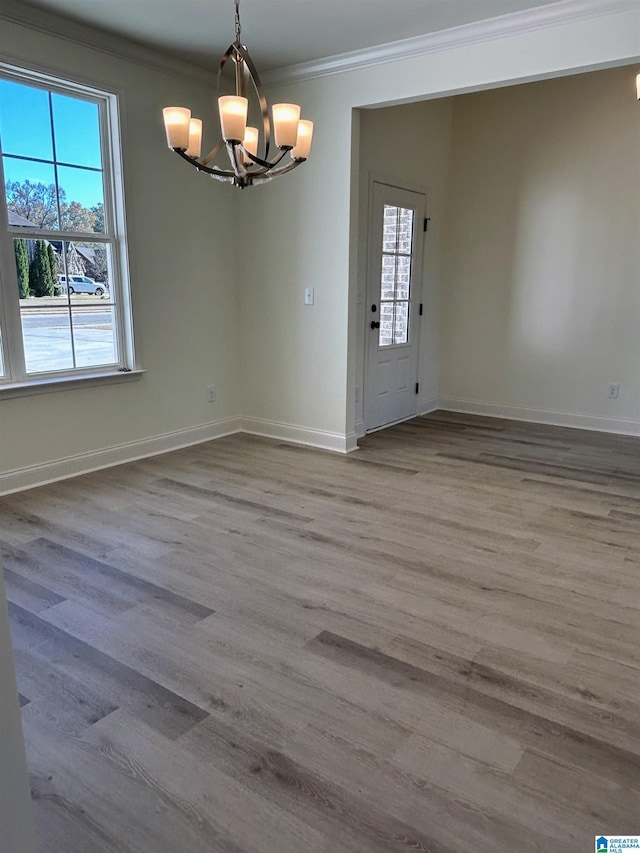 unfurnished dining area with crown molding, wood finished floors, baseboards, and a wealth of natural light