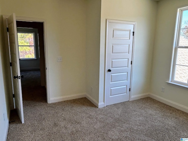 unfurnished room featuring baseboards, plenty of natural light, and carpet flooring