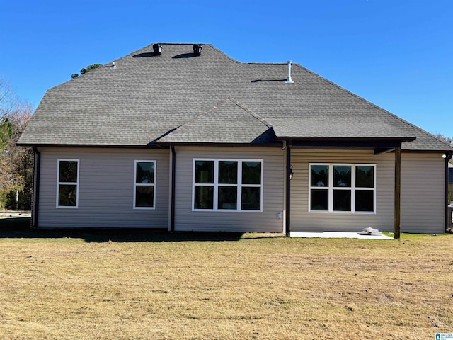 back of house featuring a lawn and roof with shingles