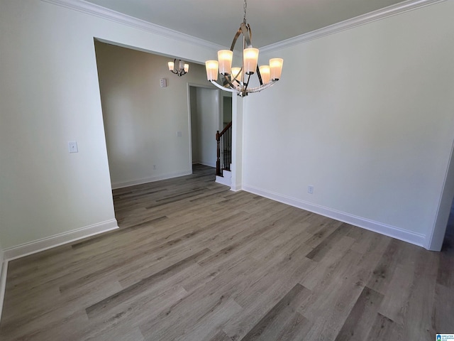 unfurnished dining area with a notable chandelier, wood finished floors, stairway, crown molding, and baseboards