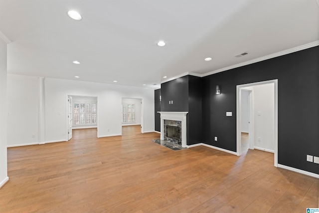 unfurnished living room featuring ornamental molding, light wood-type flooring, and a premium fireplace