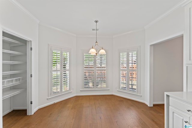 unfurnished dining area featuring crown molding, light hardwood / wood-style flooring, and a notable chandelier