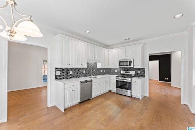 kitchen featuring appliances with stainless steel finishes, tasteful backsplash, white cabinetry, sink, and light wood-type flooring