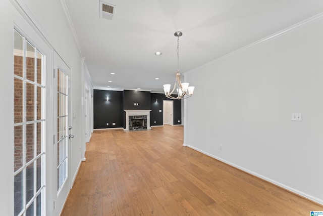 empty room with light hardwood / wood-style flooring, french doors, crown molding, and an inviting chandelier