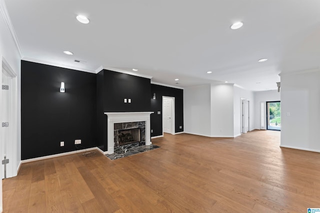 unfurnished living room with ornamental molding, light wood-type flooring, and a premium fireplace