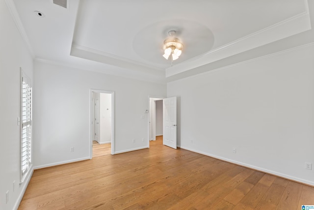 unfurnished room featuring a healthy amount of sunlight, light hardwood / wood-style flooring, ceiling fan, and a tray ceiling