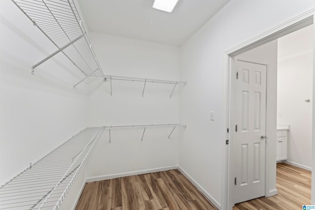 walk in closet with light hardwood / wood-style flooring