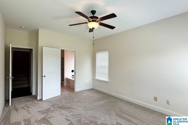 unfurnished bedroom with ensuite bath, light carpet, and ceiling fan