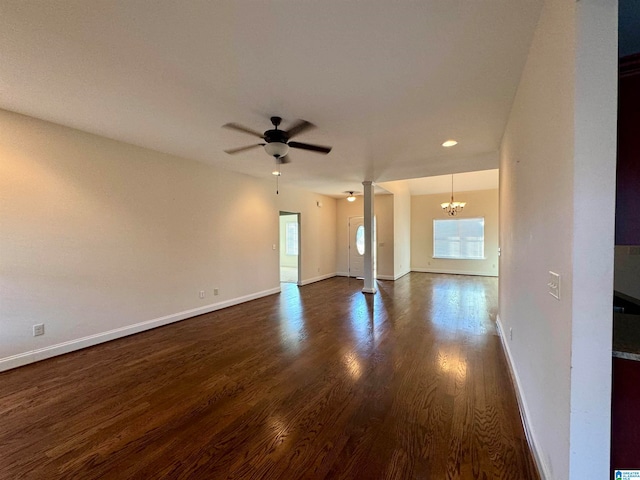 empty room featuring ceiling fan with notable chandelier and dark hardwood / wood-style flooring