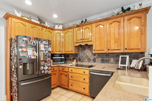 kitchen with sink, light tile floors, ornamental molding, appliances with stainless steel finishes, and backsplash