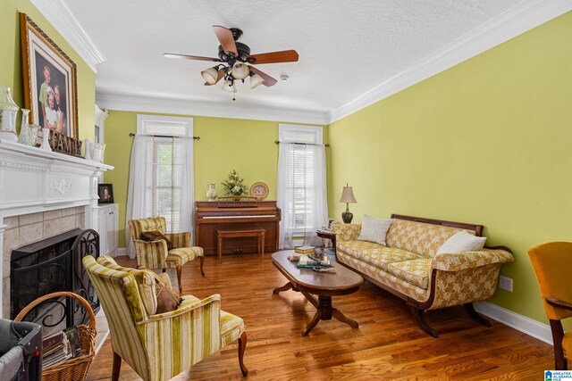 living room with ceiling fan, crown molding, a tile fireplace, and hardwood / wood-style floors