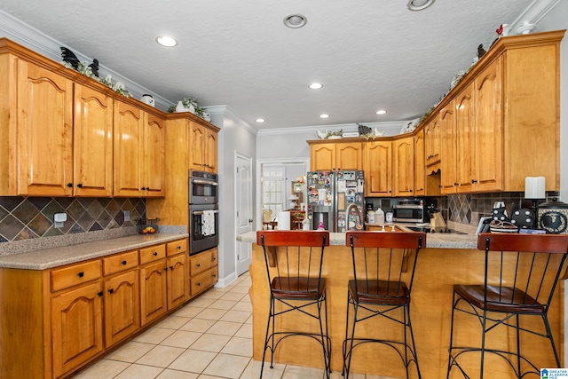 kitchen featuring a breakfast bar area, ornamental molding, appliances with stainless steel finishes, and tasteful backsplash