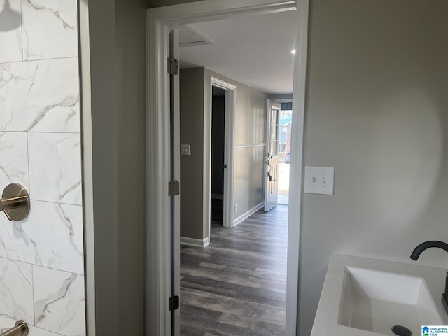 hallway featuring dark wood-type flooring, a sink, and baseboards