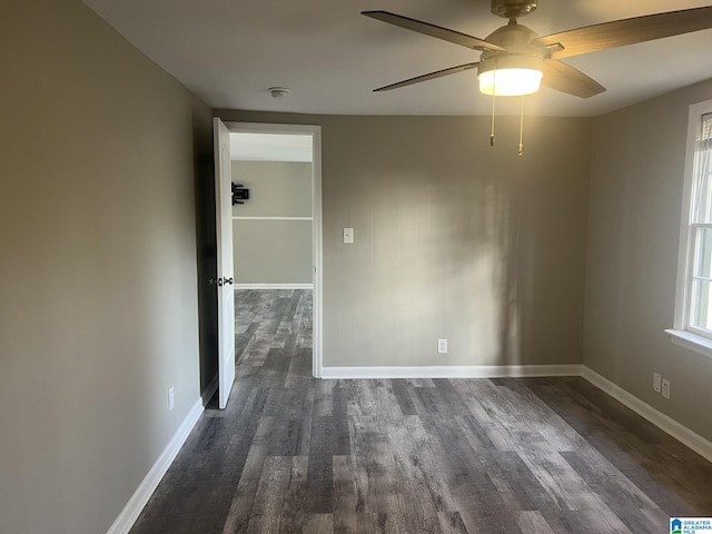 spare room featuring dark wood-style flooring, a ceiling fan, and baseboards