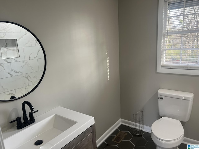 half bathroom featuring tile patterned flooring, toilet, visible vents, vanity, and baseboards