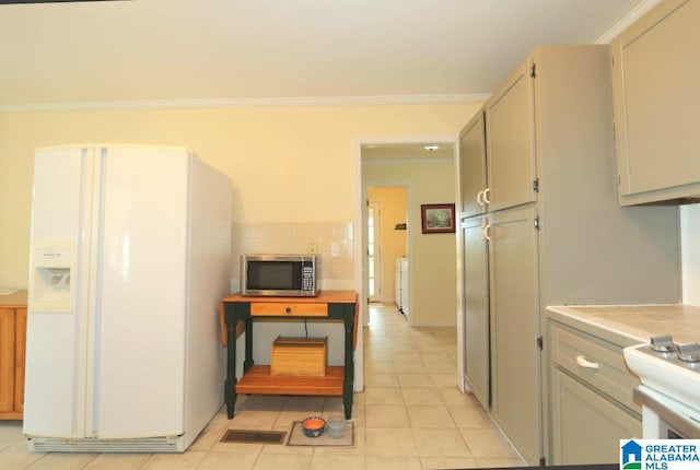 kitchen with tasteful backsplash, ornamental molding, white refrigerator with ice dispenser, and light tile patterned floors