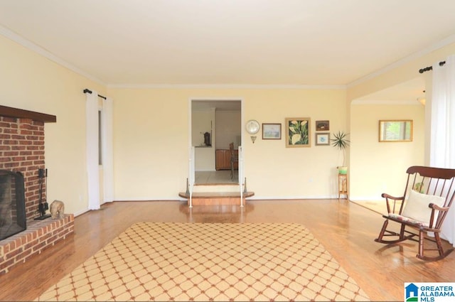 sitting room featuring crown molding, wood-type flooring, a brick fireplace, and brick wall