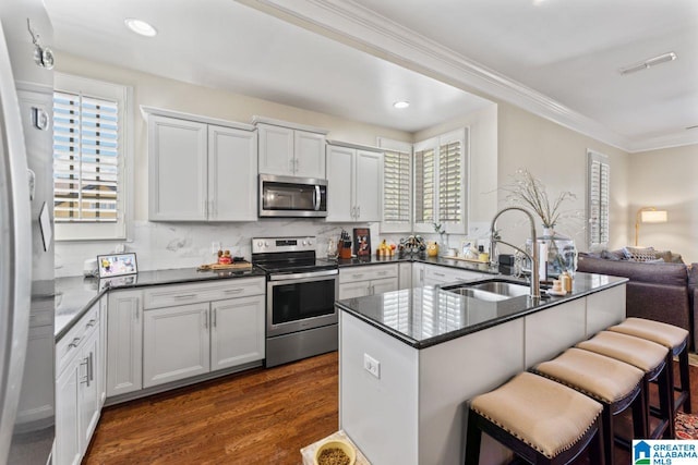 kitchen featuring appliances with stainless steel finishes, tasteful backsplash, sink, dark hardwood / wood-style floors, and white cabinets