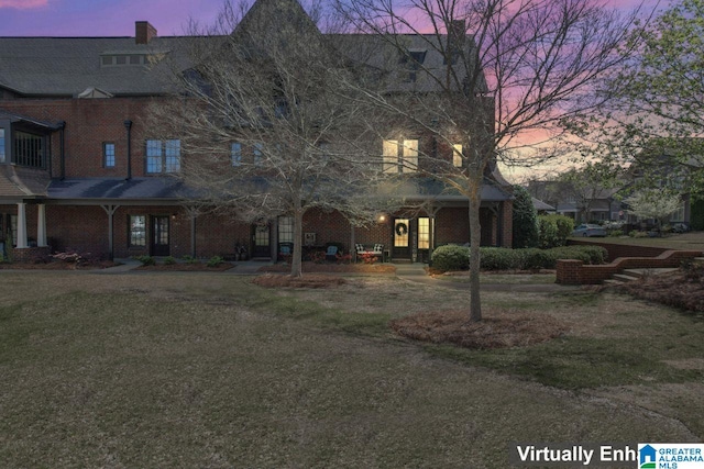 back house at dusk featuring a yard