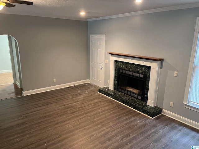 unfurnished living room featuring ceiling fan, ornamental molding, a fireplace, and dark hardwood / wood-style floors