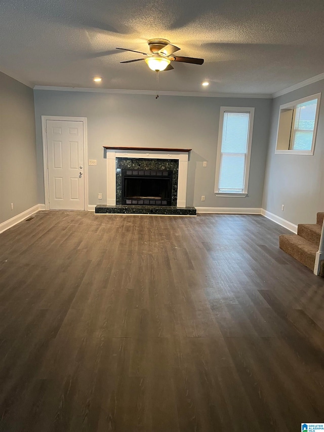 unfurnished living room with ceiling fan, a tile fireplace, dark hardwood / wood-style floors, and a textured ceiling