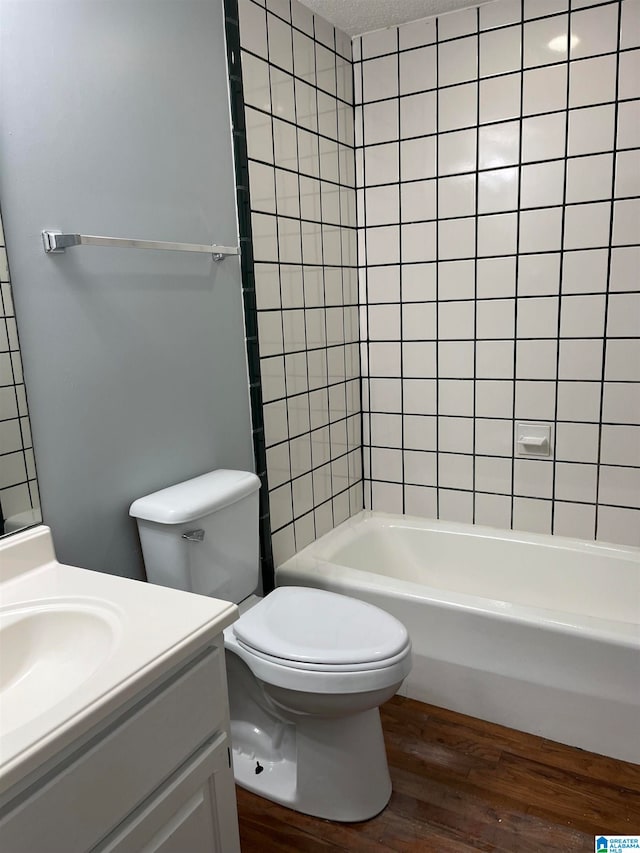 full bathroom featuring tiled shower / bath combo, vanity, wood-type flooring, and toilet