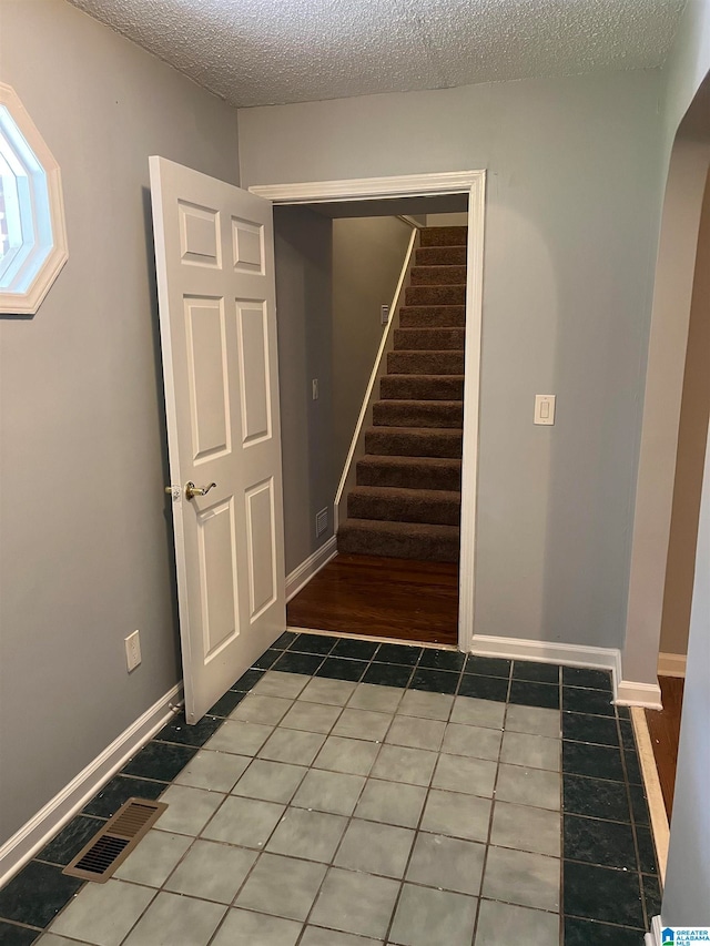 stairs featuring a textured ceiling and dark wood-type flooring