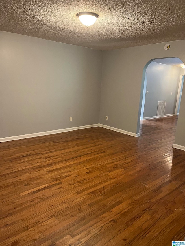 empty room featuring a textured ceiling and dark wood-type flooring