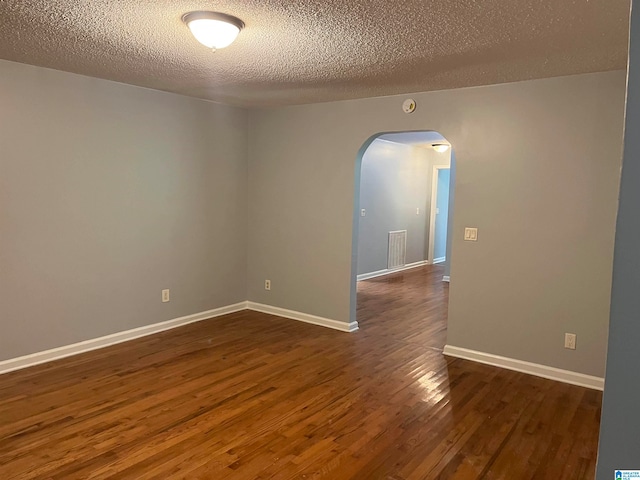 empty room featuring a textured ceiling and dark wood-type flooring